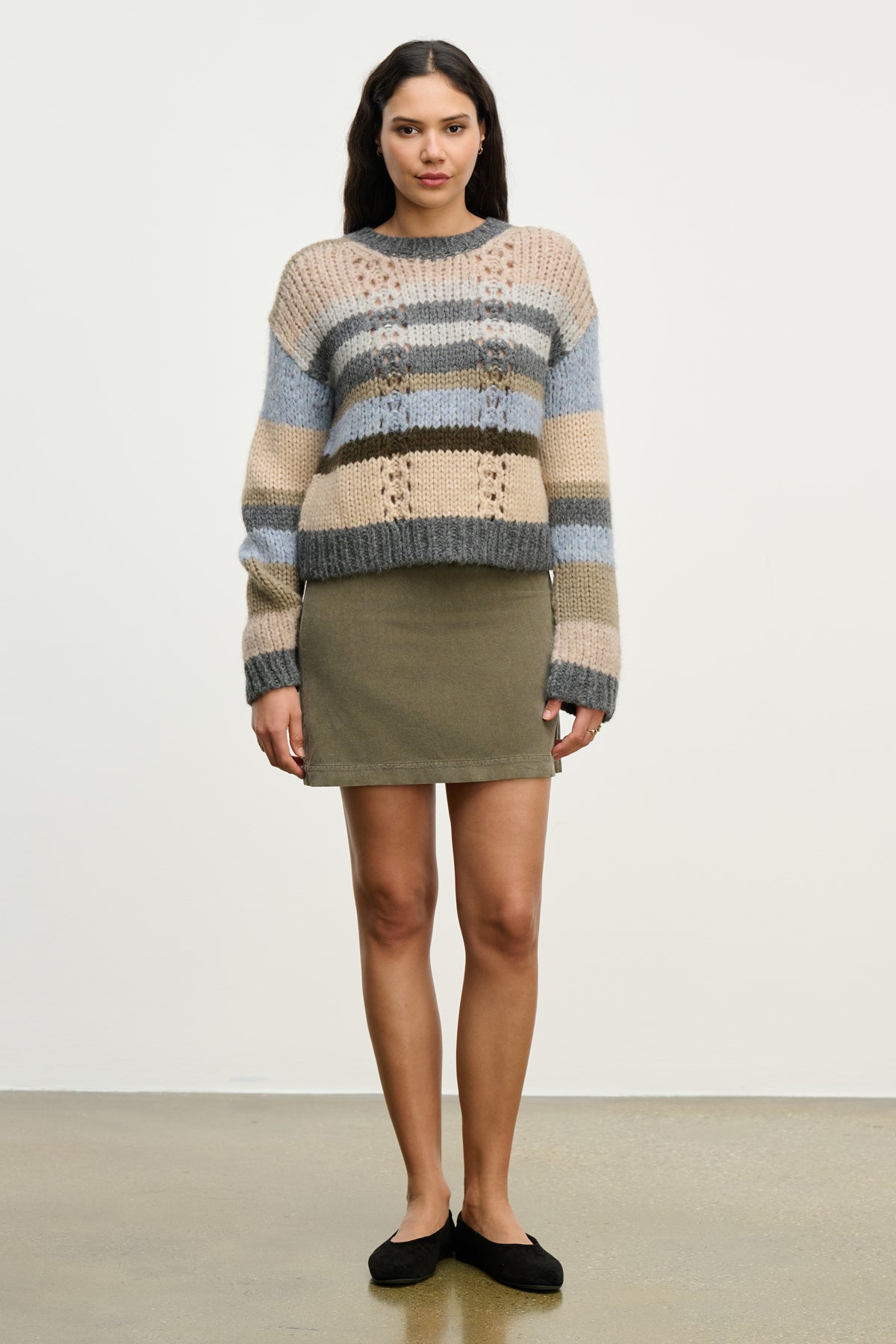 A woman stands facing forward in the LIZA CORDUROY SKIRT by Velvet by Graham & Spencer, paired with a striped knit sweater and black flats against a plain light background.-39815234814145