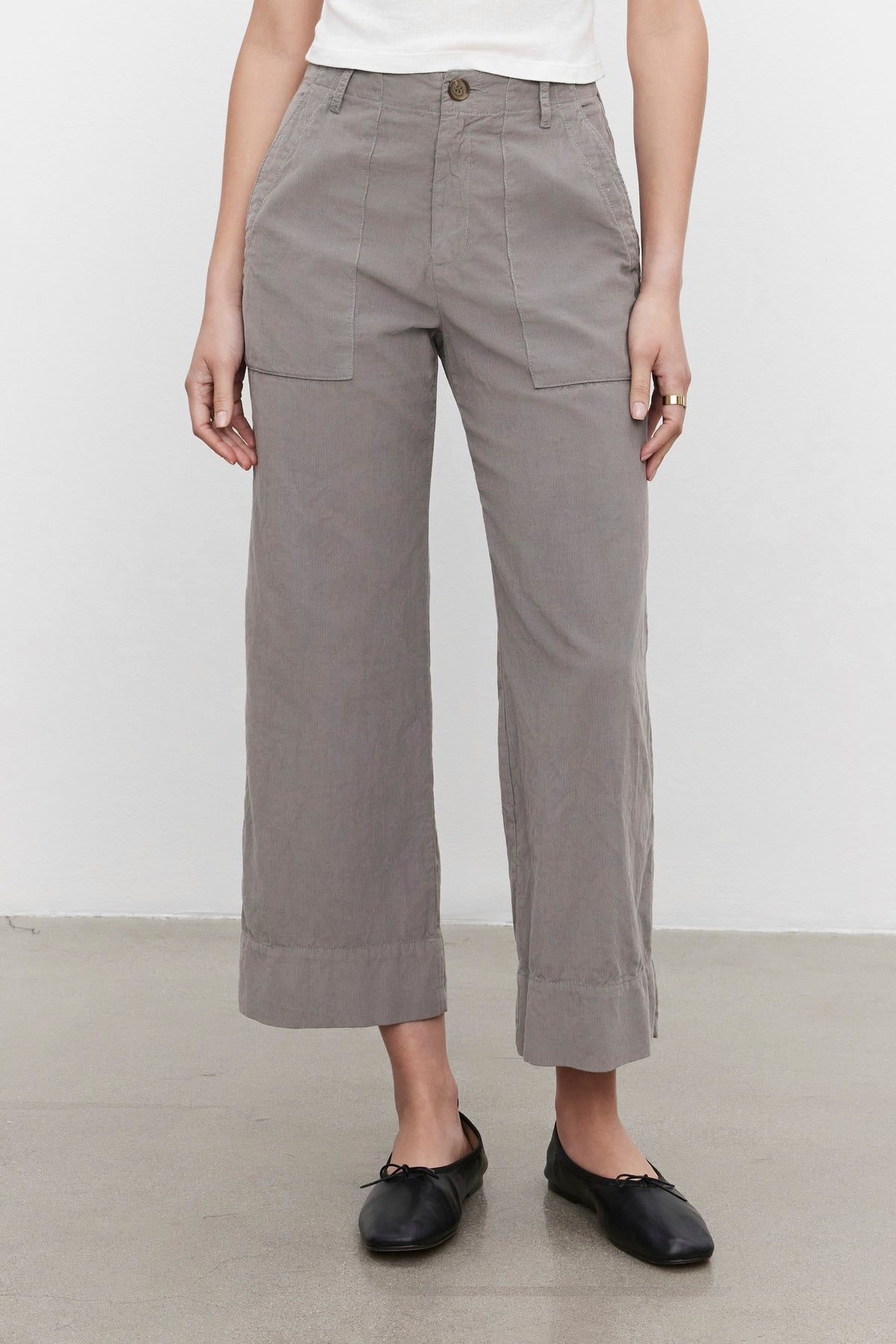 A person is wearing the flattering silhouette VERA CORDUROY PANT in gray by Velvet by Graham & Spencer, paired with a white top and black shoes. The photo is taken indoors against a plain background.-37676942459073