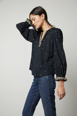 The model is wearing Velvet by Graham & Spencer ANIA EMBROIDERED BOHO TOP and jeans.