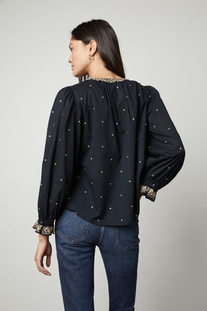 The back view of a woman wearing ANIA EMBROIDERED BOHO TOP by Velvet by Graham & Spencer jeans.