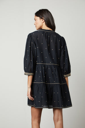 The back view of a woman wearing a Velvet by Graham & Spencer KILEY EMBROIDERED BOHO DRESS.
