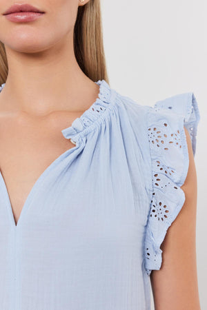 Close-up of a woman wearing a Velvet by Graham & Spencer GRACE DRESS with ruffled sleeves and eyelet details on the shoulder.