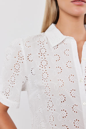 Close-up of a woman wearing a white, cotton OLIVIA BLOUSE with eyelet details and a pointed collar by Velvet by Graham & Spencer.