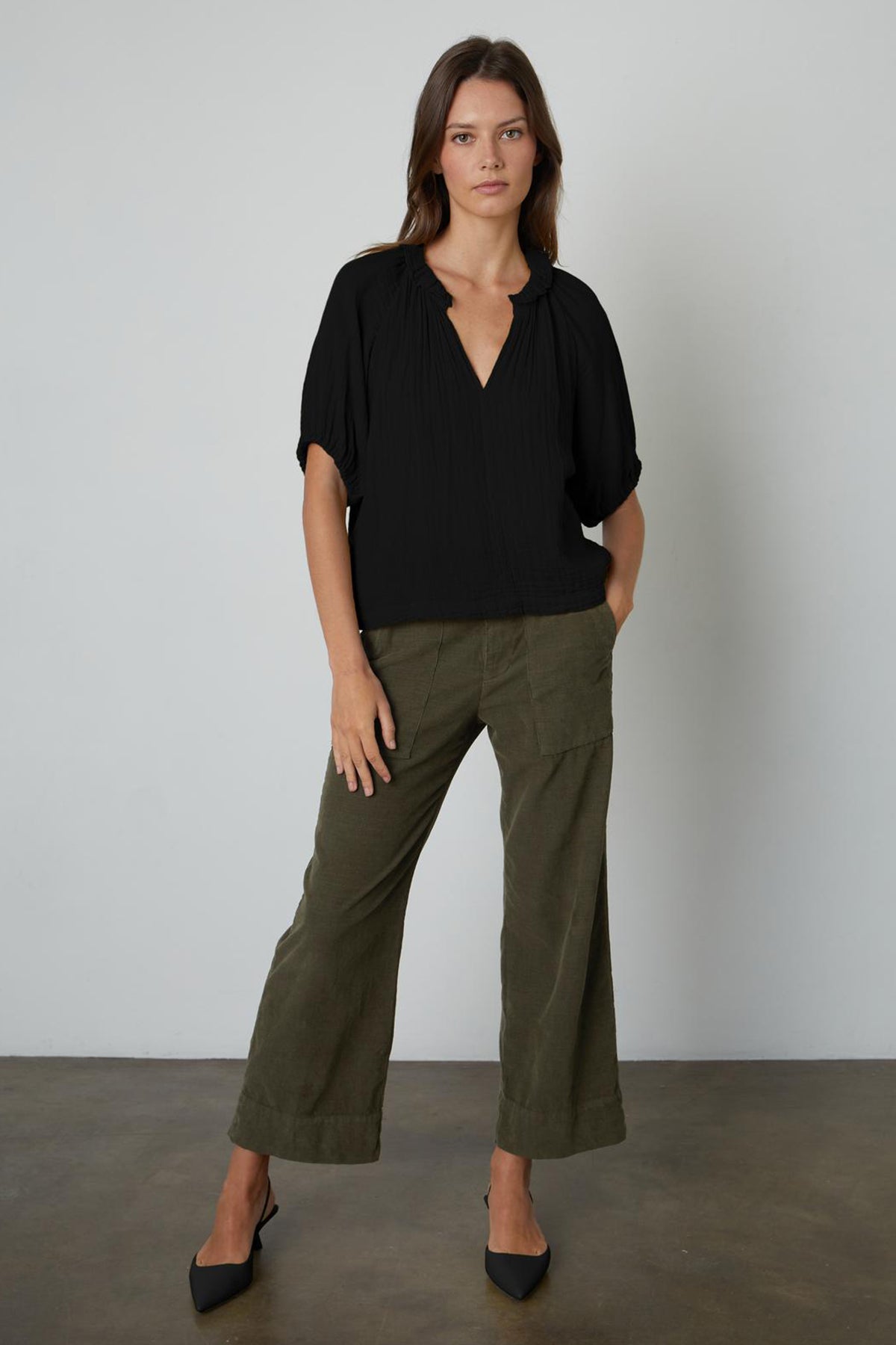   The model is wearing a black blouse and Velvet by Graham & Spencer's VERA CORDUROY WIDE LEG PANT in olive green. 
