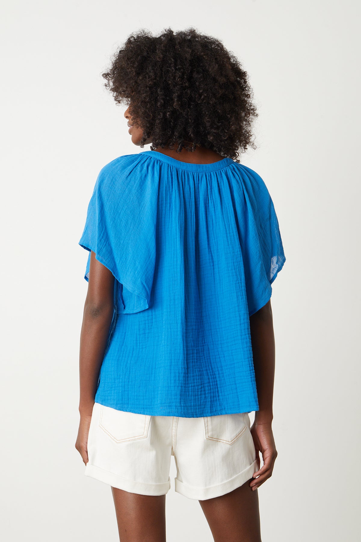   the back view of a woman wearing a Velvet by Graham & Spencer BELLE COTTON GAUZE BLOUSE and shorts. 