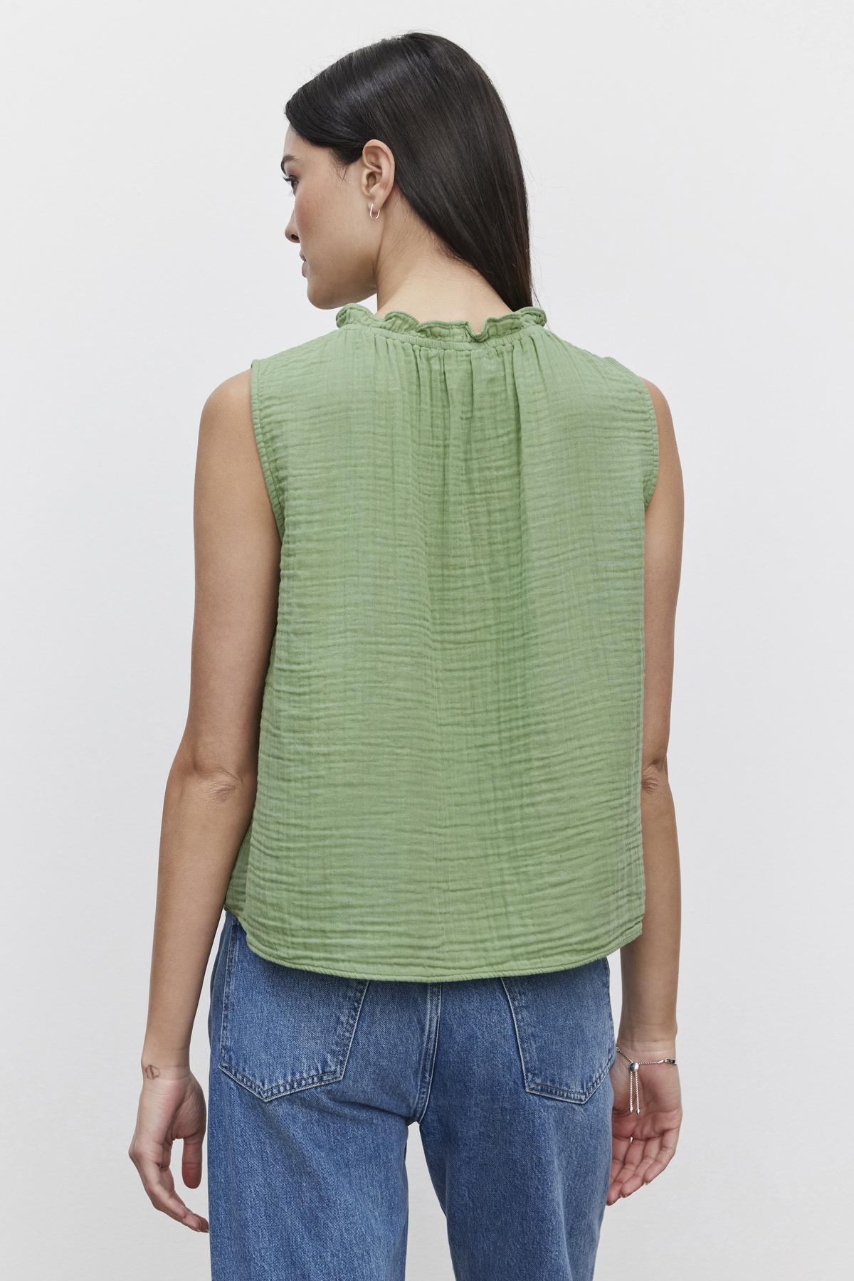 A woman seen from behind wearing a Velvet by Graham & Spencer BIANCA COTTON GAUZE TANK TOP with an elastic neckline and blue jeans.-36443616248001