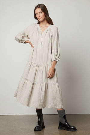 The model is wearing a Velvet by Graham & Spencer DIXON COTTON GAUZE TIERED DRESS in beige.