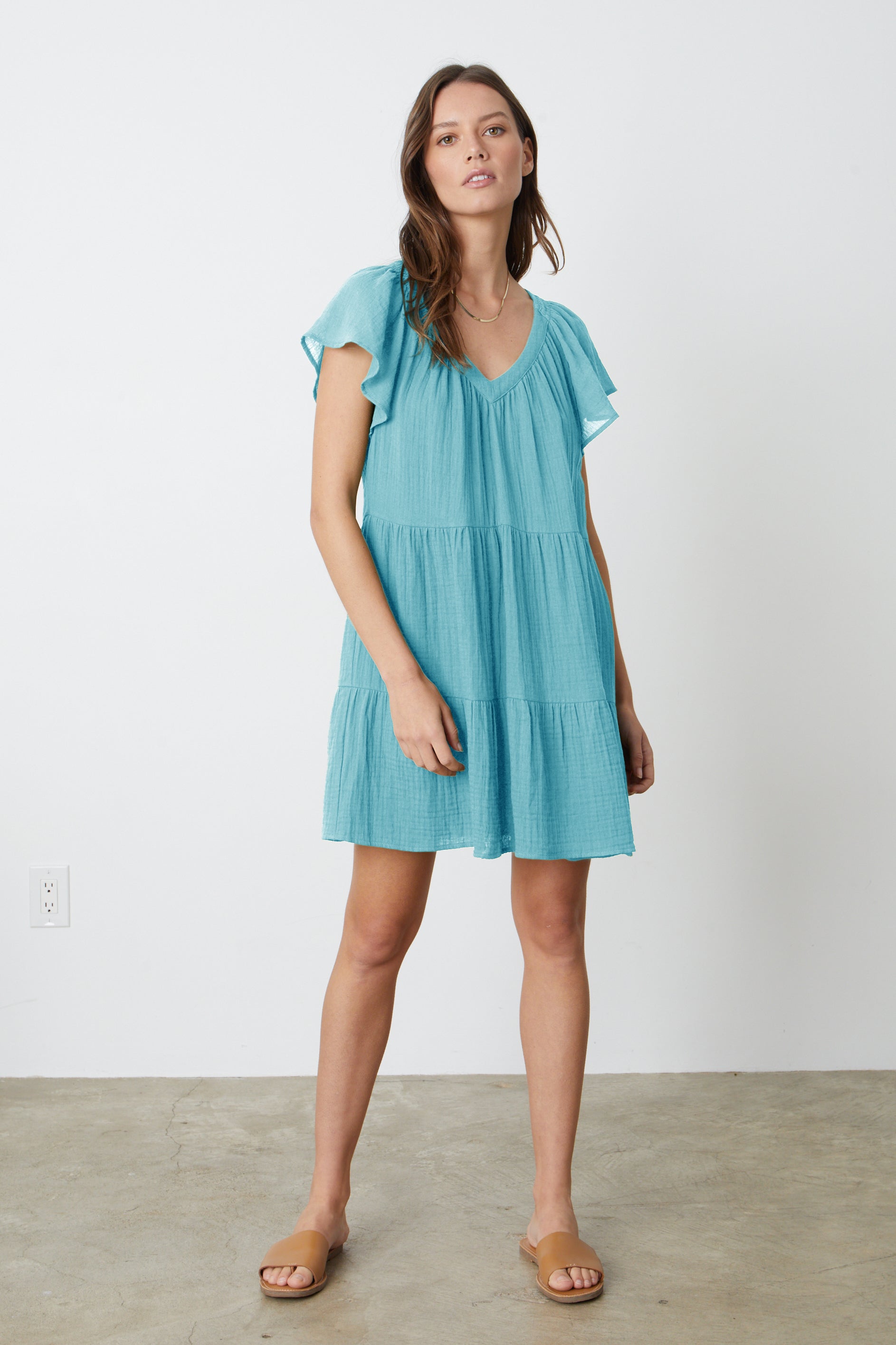  A model wearing a Velvet by Graham & Spencer ELEANOR COTTON GAUZE TIERED DRESS in aqua blue with sandals. 