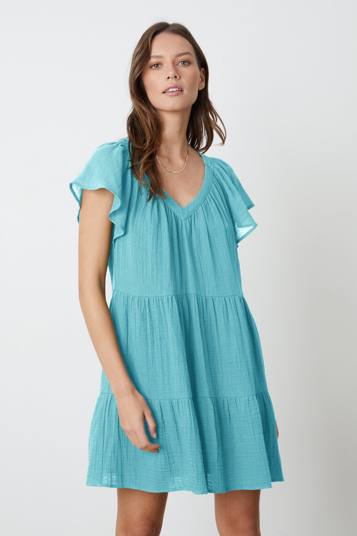 A woman wearing the Velvet by Graham & Spencer Eleanor Cotton Gauze Tiered Dress in aqua blue with ruffled hem.-26577372348609