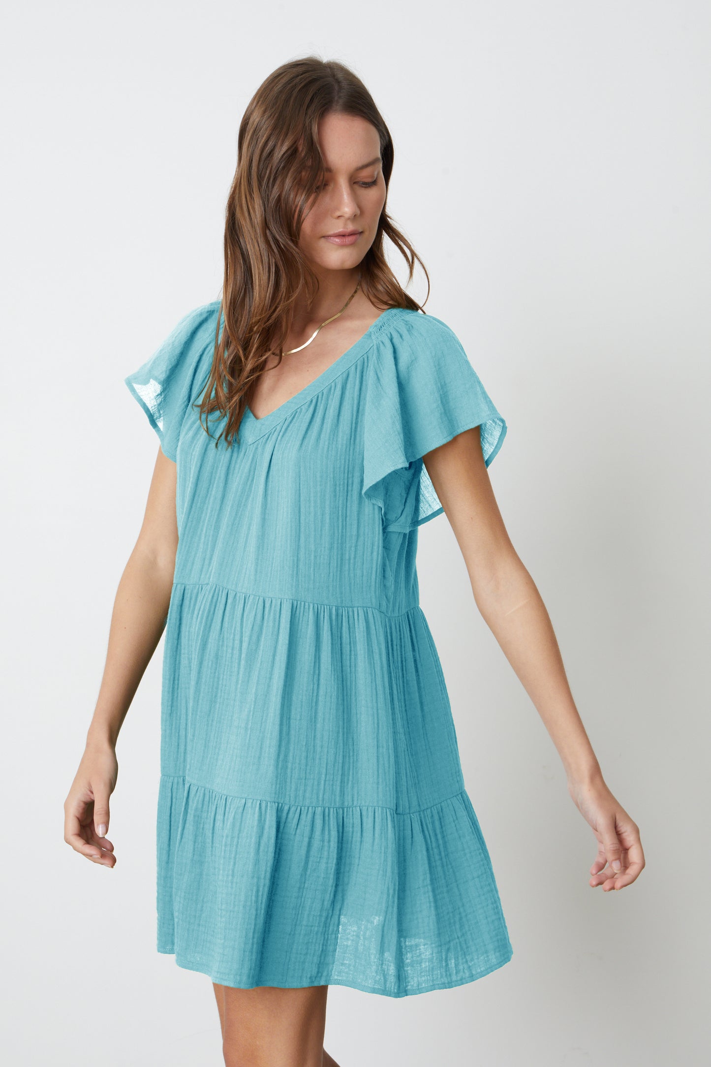 The model is wearing a Velvet by Graham & Spencer ELEANOR COTTON GAUZE TIERED DRESS in aqua blue with ruffles.-26577372315841