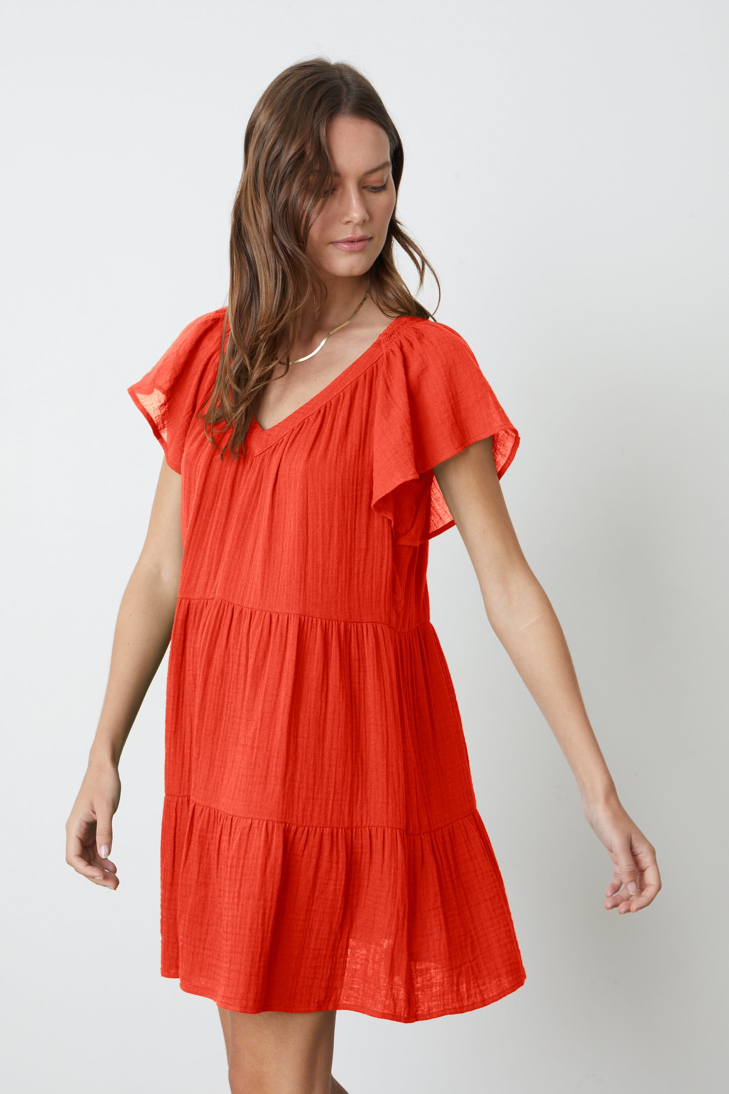 A woman is wearing the Velvet by Graham & Spencer ELEANOR COTTON GAUZE TIERED DRESS with ruffles.-26577372446913