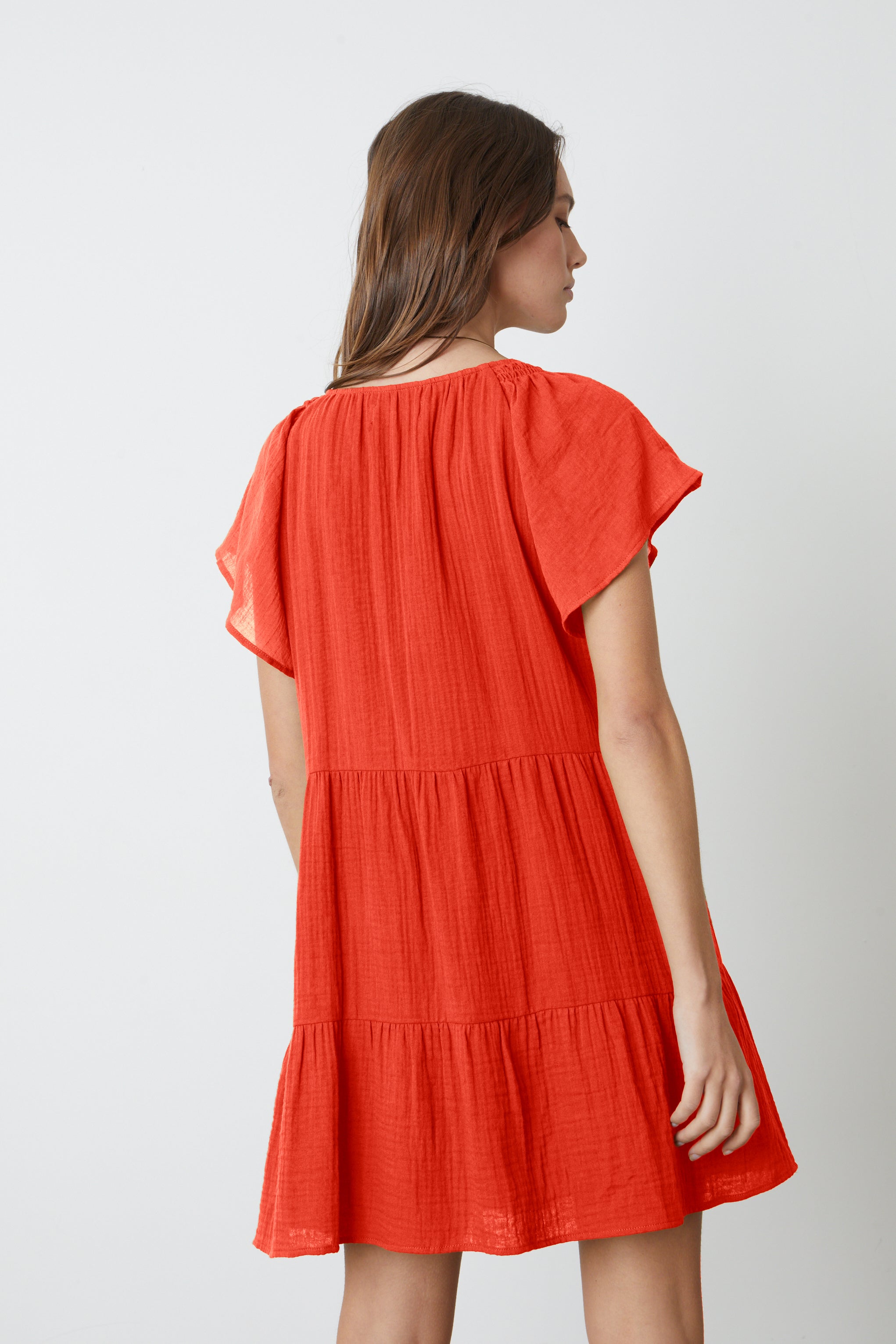   The back view of a woman in an Eleanor Cotton Gauze Tiered Dress by Velvet by Graham & Spencer. 