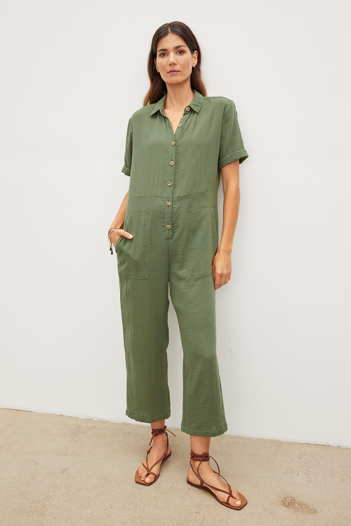   A relaxed model donning an ELIA COTTON GAUZE JUMPSUIT by Velvet by Graham & Spencer and sandals. 