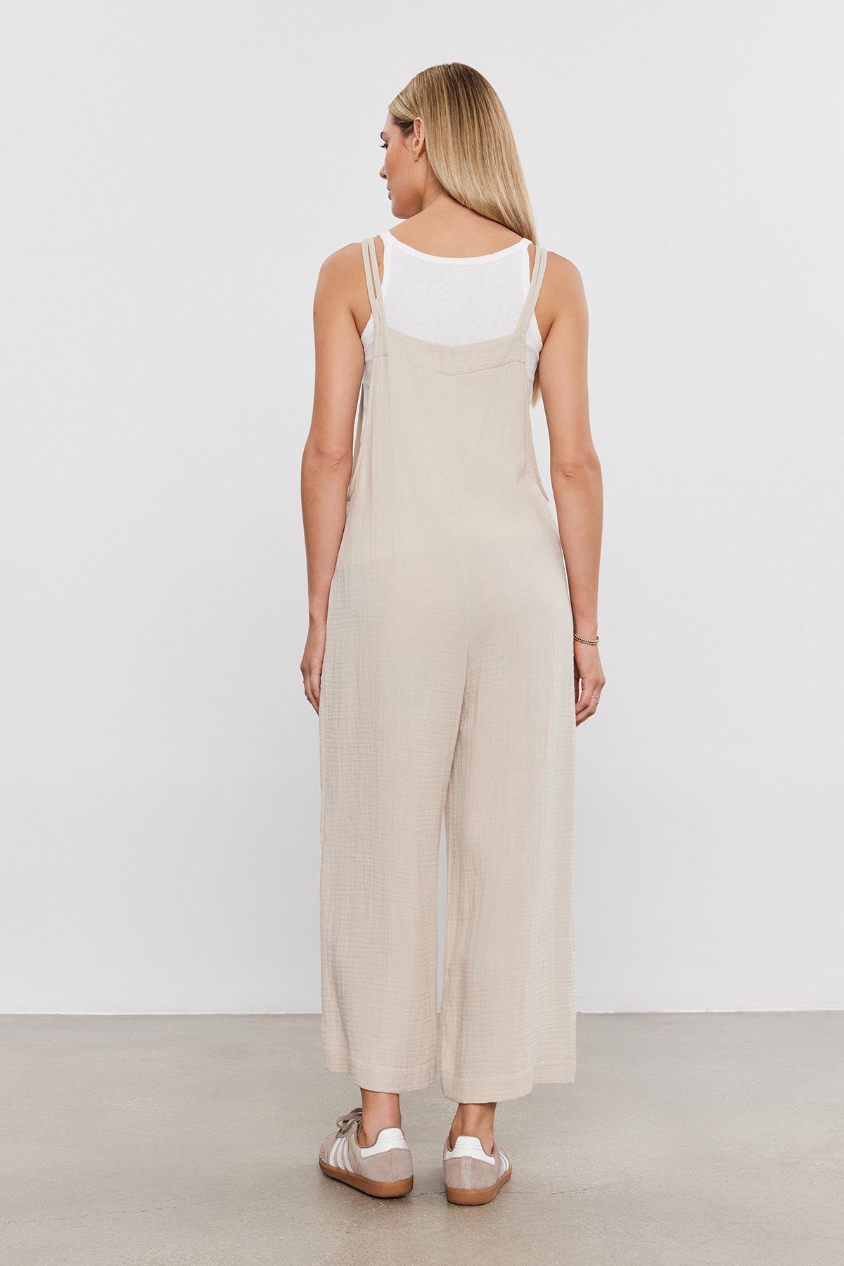 Woman standing facing away, wearing a Velvet by Graham & Spencer EVERLEE COTTON GAUZE JUMPSUIT with wide legs and white sandals on a plain background.-36910029144257