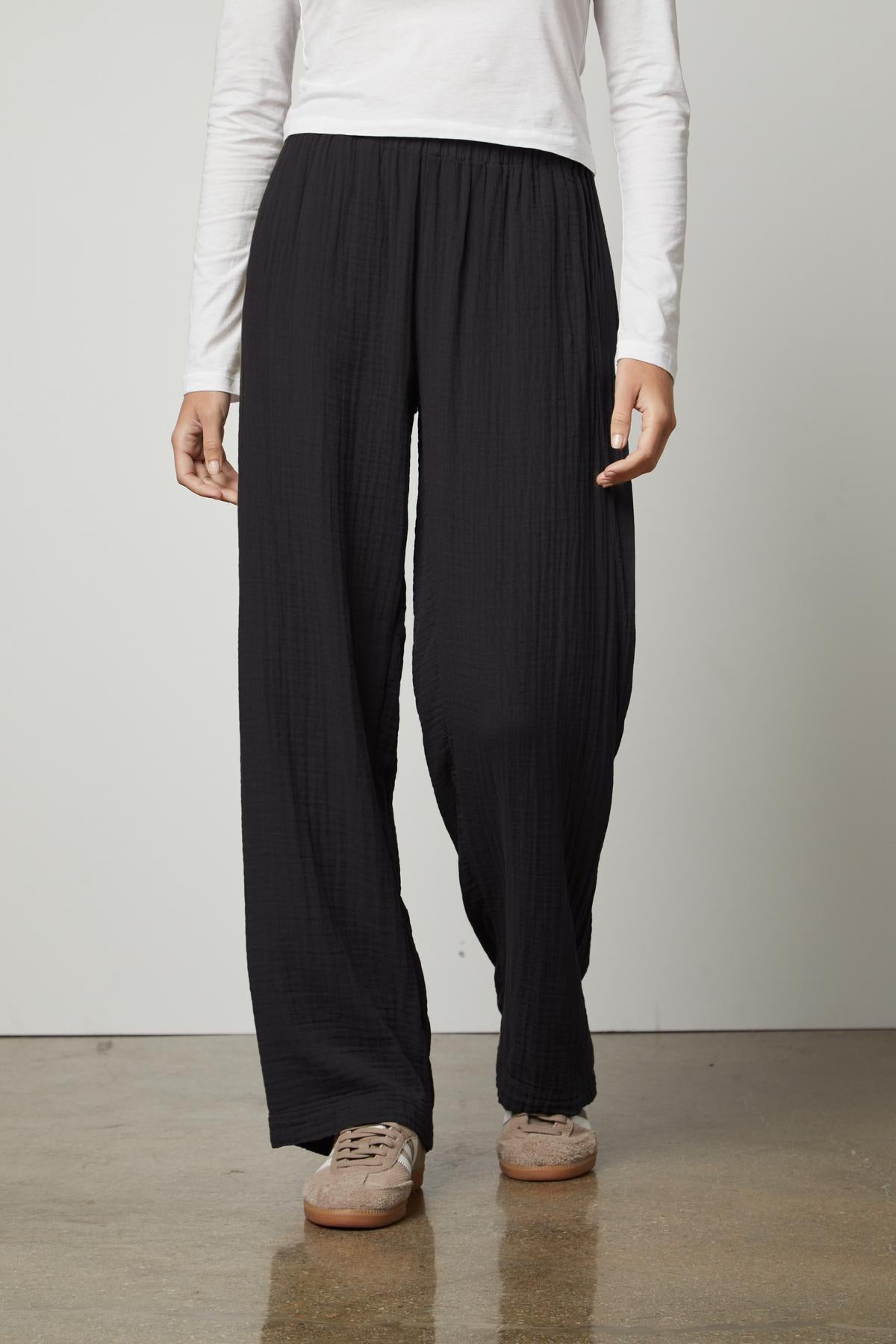   A woman wearing Velvet by Graham & Spencer black straight leg pants with an elastic waistband and a white t-shirt. 