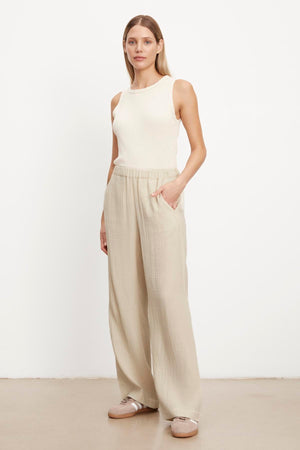 The model is wearing a white tank top and beige JERRY COTTON GAUZE PANT with an elastic waistband by Velvet by Graham & Spencer.