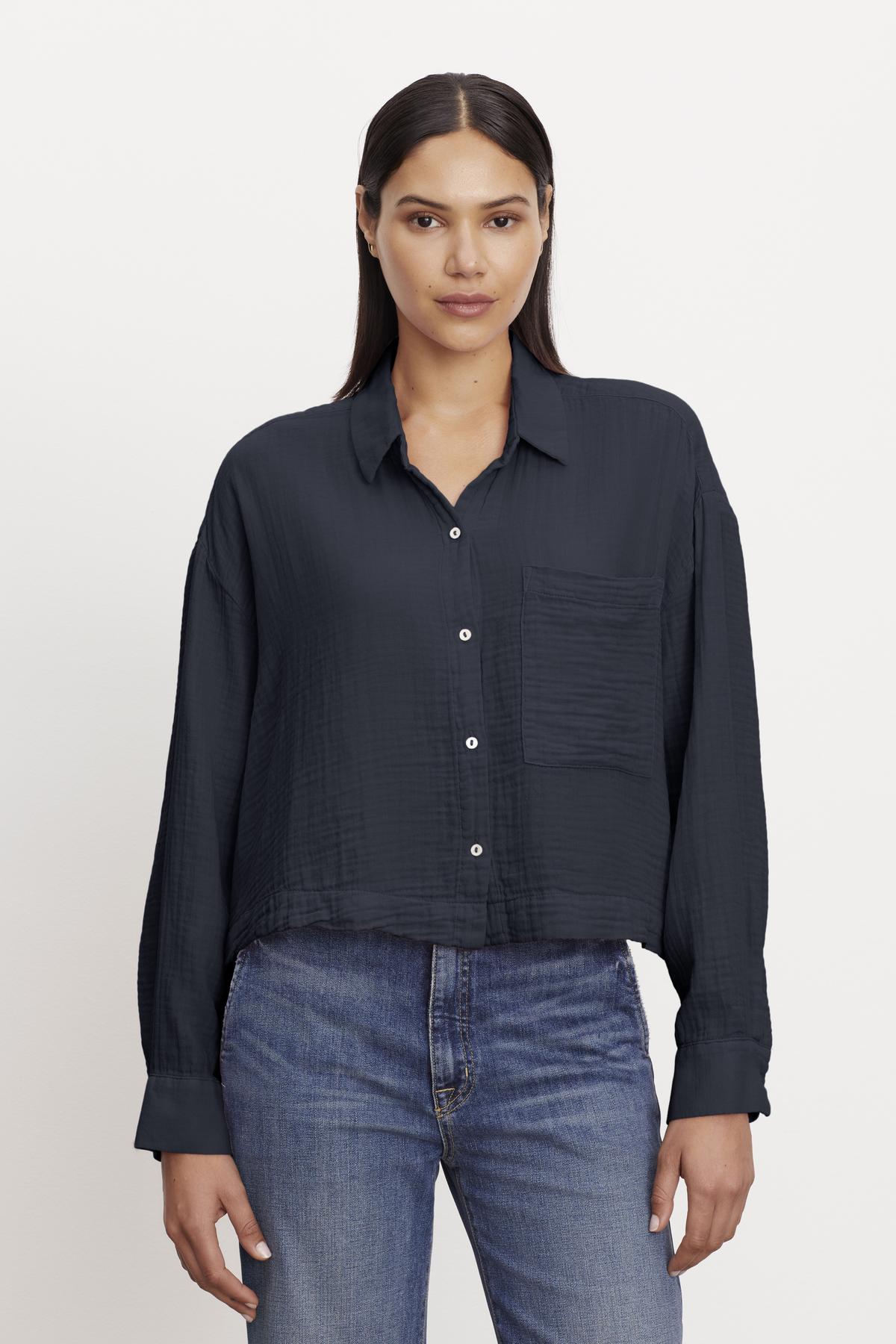   Woman in a casual black LANA COTTON GAUZE BUTTON-UP SHIRT and blue jeans by Velvet by Graham & Spencer. 