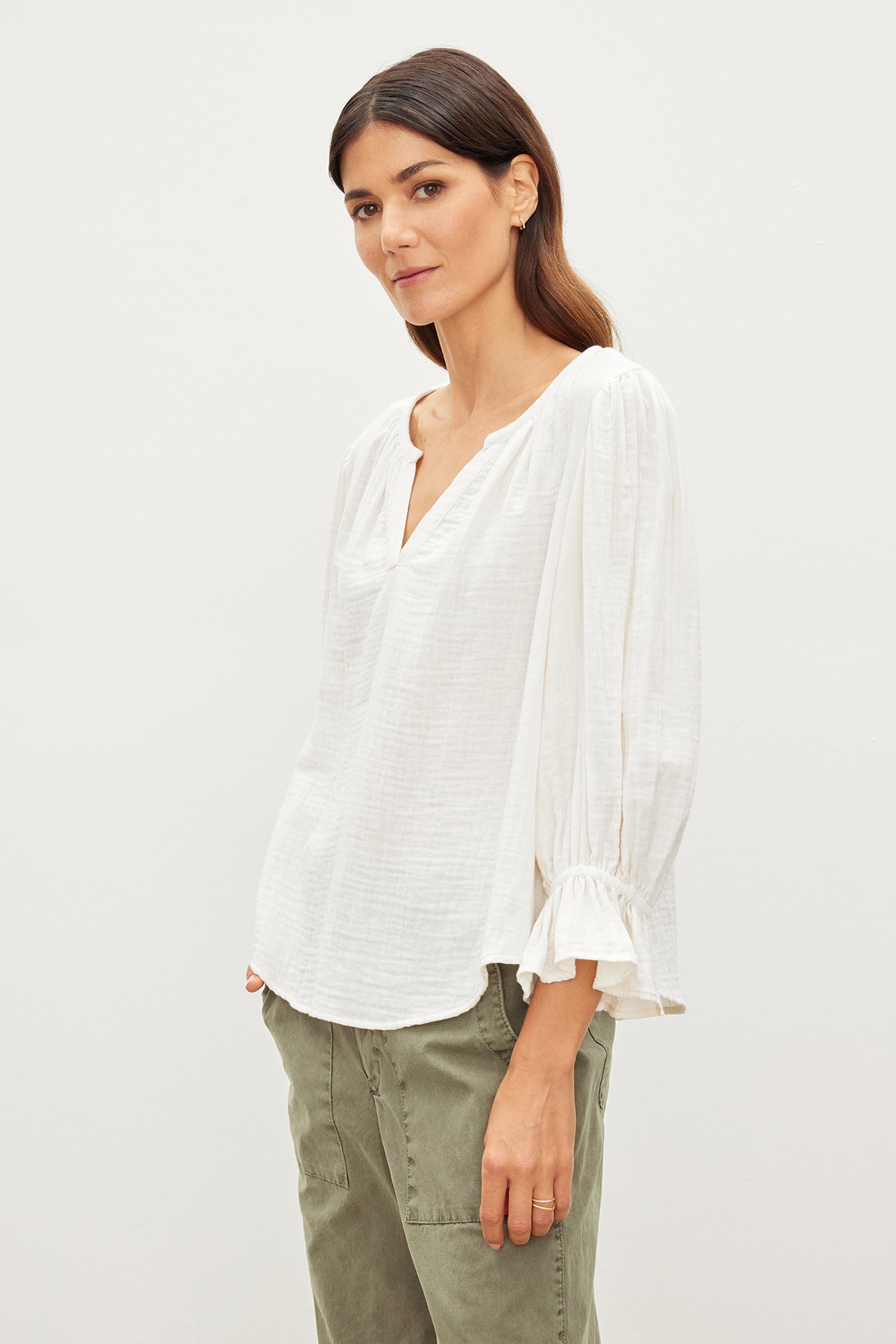   The model is effortlessly showcasing a relaxed fit in a Velvet by Graham & Spencer MILLY COTTON GAUZE PEASANT TOP, paired with stylish green pants. 