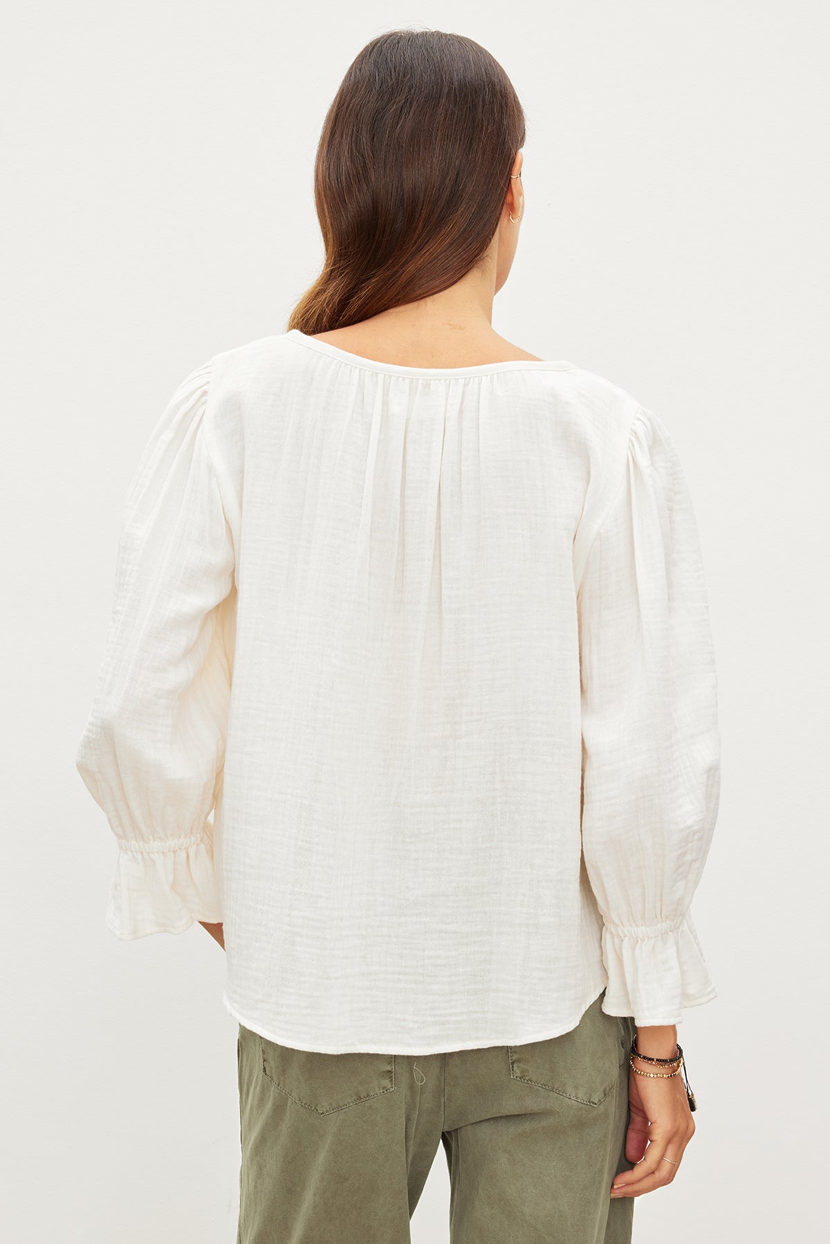 The back view of a woman wearing a MILLY COTTON GAUZE PEASANT TOP by Velvet by Graham & Spencer and green pants crafted from cotton gauze for effortless sophistication.-35967572902081