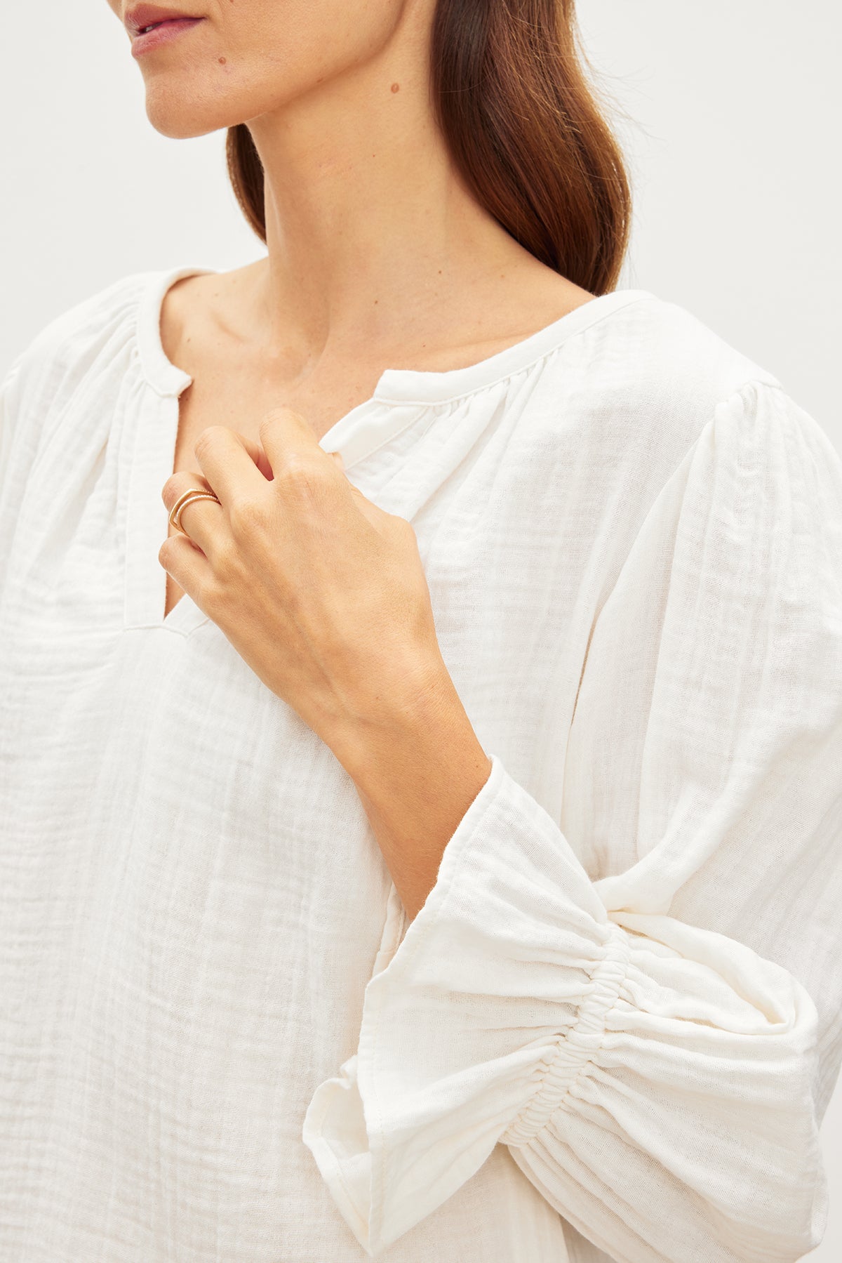   A woman wearing a white blouse, the MILLY COTTON GAUZE PEASANT TOP by Velvet by Graham & Spencer, in relaxed fit and cotton gauze fabric, with ruffled sleeves exuding effortless sophistication. 