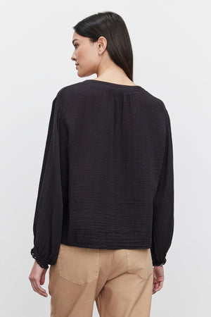 A person with long dark hair is shown from the back wearing a black Naomi Cotton Gauze Top by Velvet by Graham & Spencer and beige pants, standing against a plain white background.