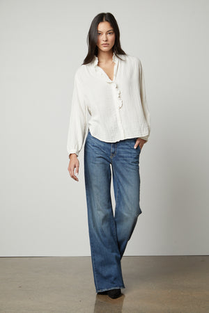 The model is wearing a TRISHA COTTON GAUZE TOP blouse by Velvet by Graham & Spencer and blue jeans.