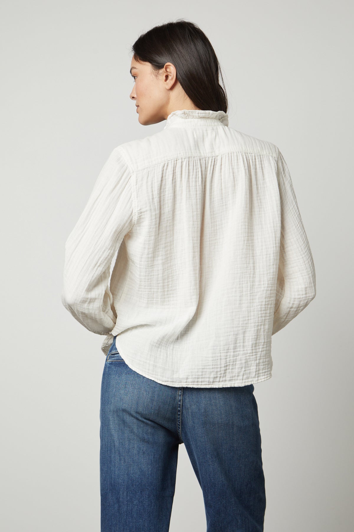 The back view of a woman wearing a TRISHA COTTON GAUZE TOP by Velvet by Graham & Spencer and jeans.-26872389042369
