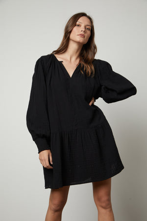 The model is wearing the VIVIANA COTTON GAUZE DRESS by Velvet by Graham & Spencer with ruffled sleeves.