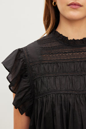 A woman wearing a Velvet by Graham & Spencer black top with ruffled ruffles called the INESSA COTTON LACE TOP.