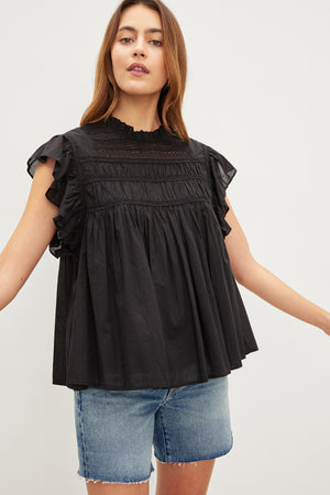 The model is wearing a Velvet by Graham & Spencer INESSA COTTON LACE TOP with ruffled sleeves.