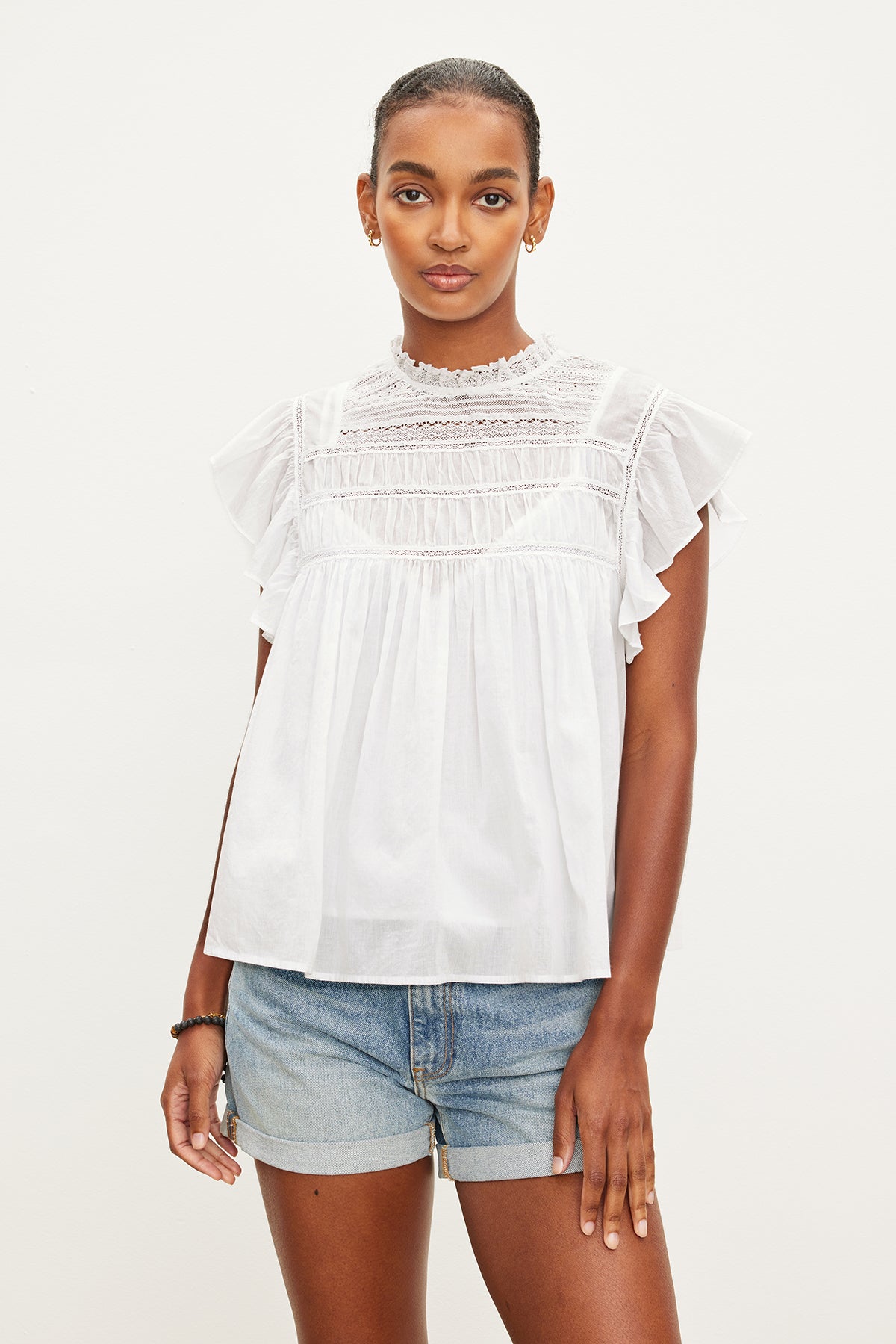   The model is wearing a Velvet by Graham & Spencer INESSA COTTON LACE TOP with ruffled sleeve. 