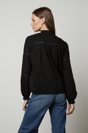 The back view of a woman wearing a Velvet by Graham & Spencer ROMY LACE BOHO TOP blouse and jeans.