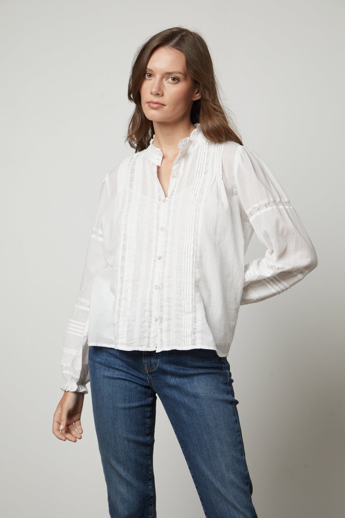 The model is wearing a white ROMY LACE BOHO TOP blouse and jeans by Velvet by Graham & Spencer.-26834995609793