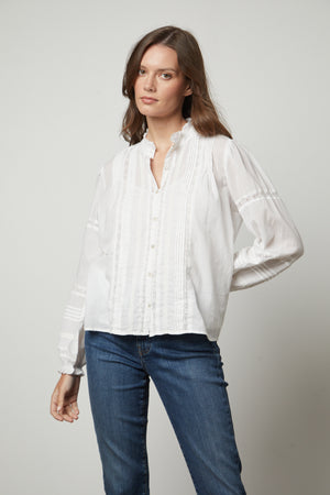 The model is wearing a white ROMY LACE BOHO TOP blouse and jeans by Velvet by Graham & Spencer.