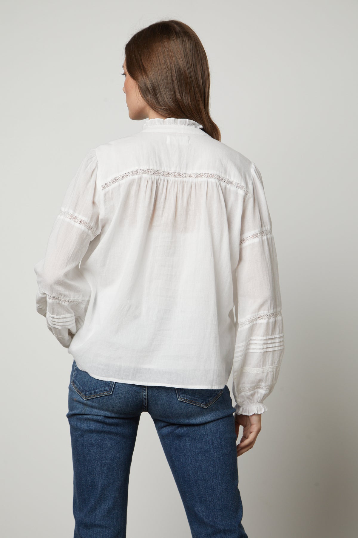   The back view of a woman wearing a Velvet by Graham & Spencer ROMY LACE BOHO TOP and jeans. 