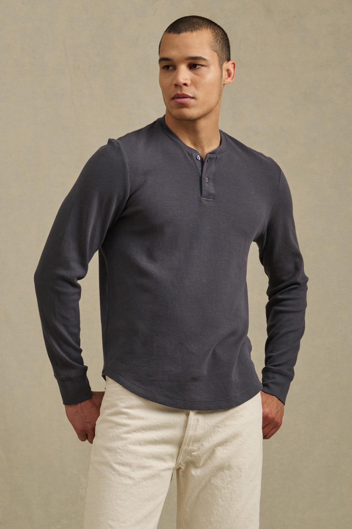 A person wearing the ARNOLD HENLEY by Velvet by Graham & Spencer in dark gray with light-colored pants stands against a neutral background.-41374344413377