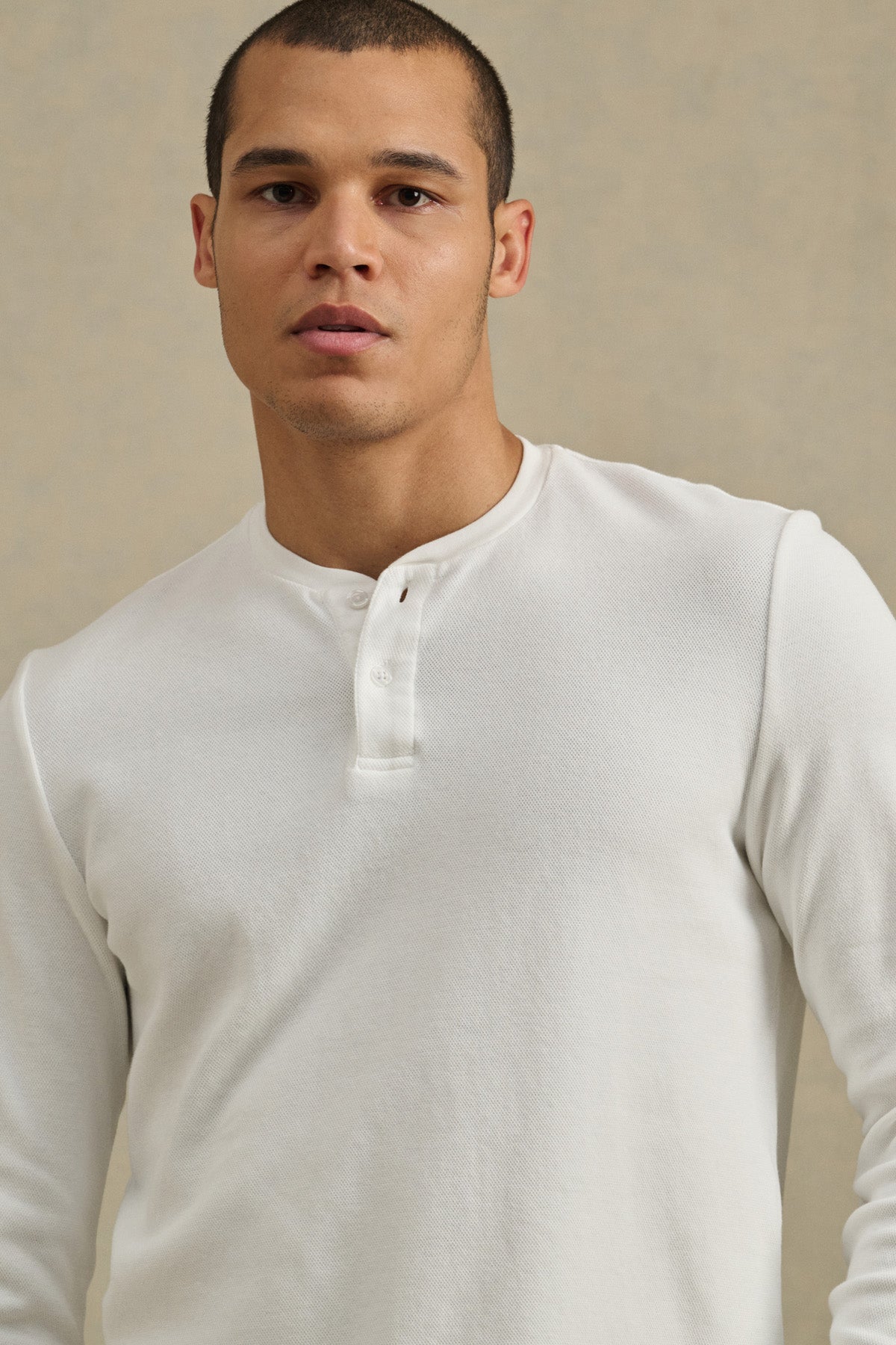 A man wearing the ARNOLD HENLEY by Velvet by Graham & Spencer stands against a plain, light-colored background, looking directly at the camera.