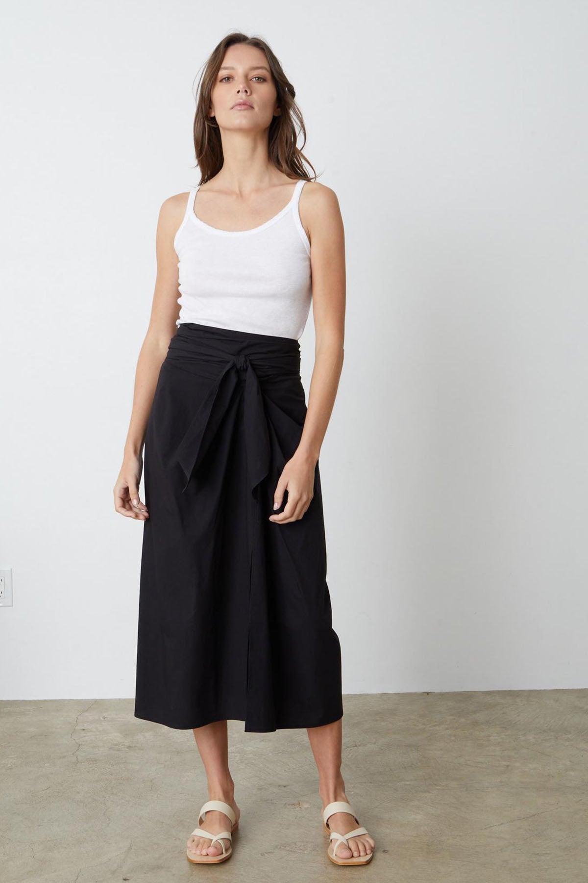   A woman wearing a LEENA TIE FRONT SKIRT by Velvet by Graham & Spencer in a summer style. 