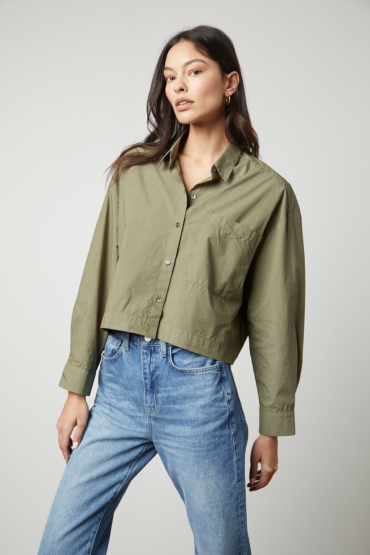 The model is wearing an oversized LUCILLE CROPPED BUTTON-UP SHIRT in olive green by Velvet by Graham & Spencer.-35503726723265