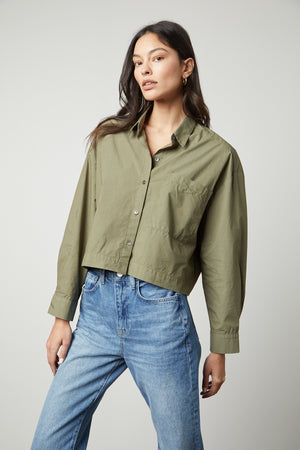 The model is wearing an oversized LUCILLE CROPPED BUTTON-UP SHIRT in olive green by Velvet by Graham & Spencer.