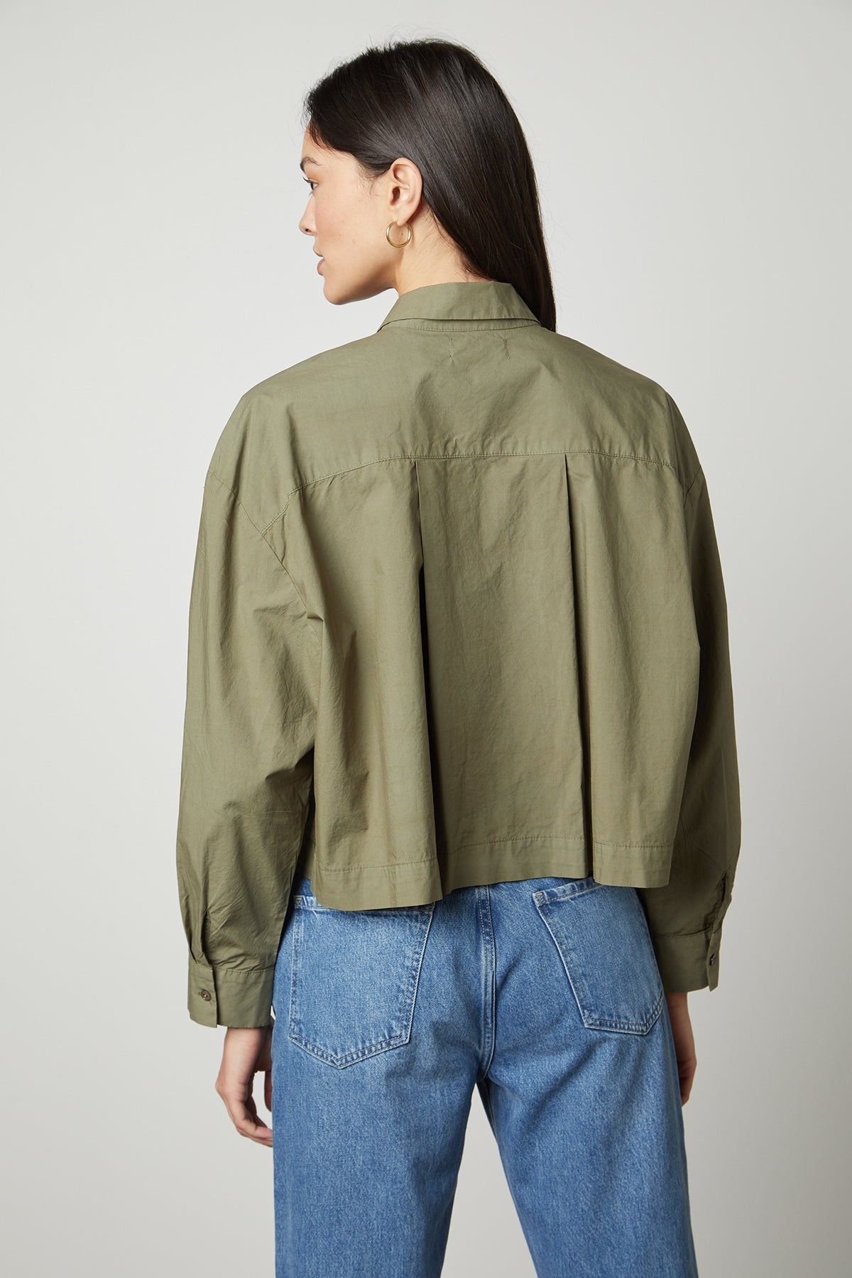 The back view of a woman wearing an oversized LUCILLE CROPPED BUTTON-UP SHIRT by Velvet by Graham & Spencer.-35503728361665