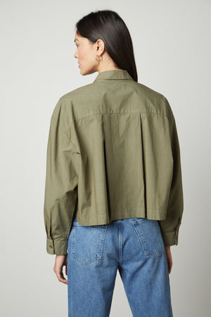 The back view of a woman wearing an oversized LUCILLE CROPPED BUTTON-UP SHIRT by Velvet by Graham & Spencer.