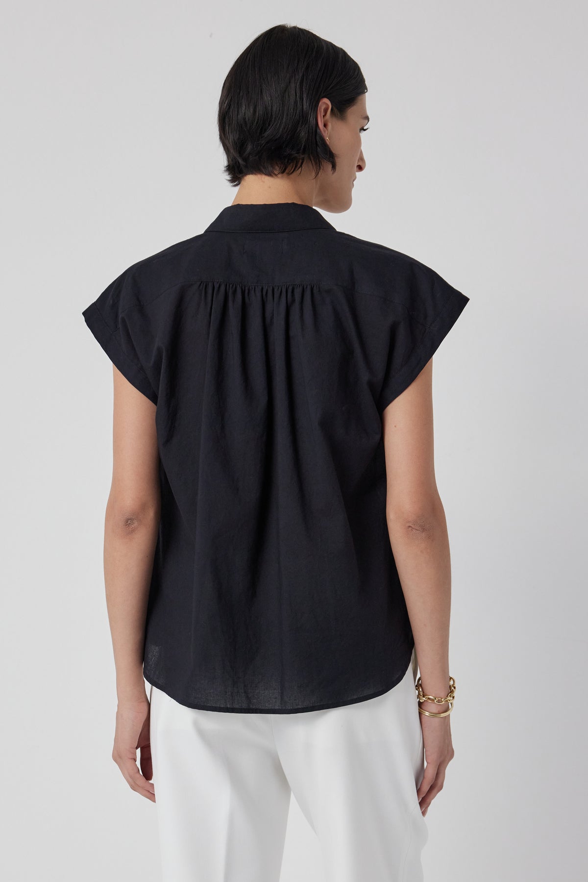   The back view of a woman wearing a black PALISADES SHIRT by Velvet by Jenny Graham and white pants. 