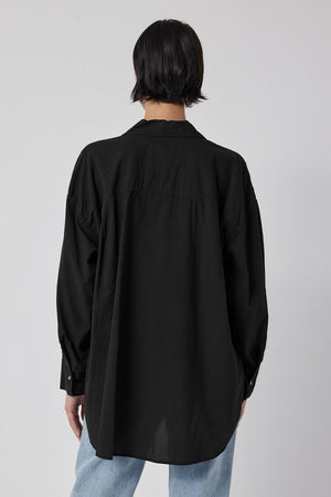 The back view of a woman wearing an oversized REDONDO BUTTON-UP SHIRT by Velvet by Jenny Graham and jeans.