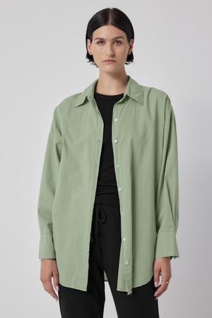 A woman wearing an oversized green REDONDO BUTTON-UP SHIRT by Velvet by Jenny Graham and black pants.