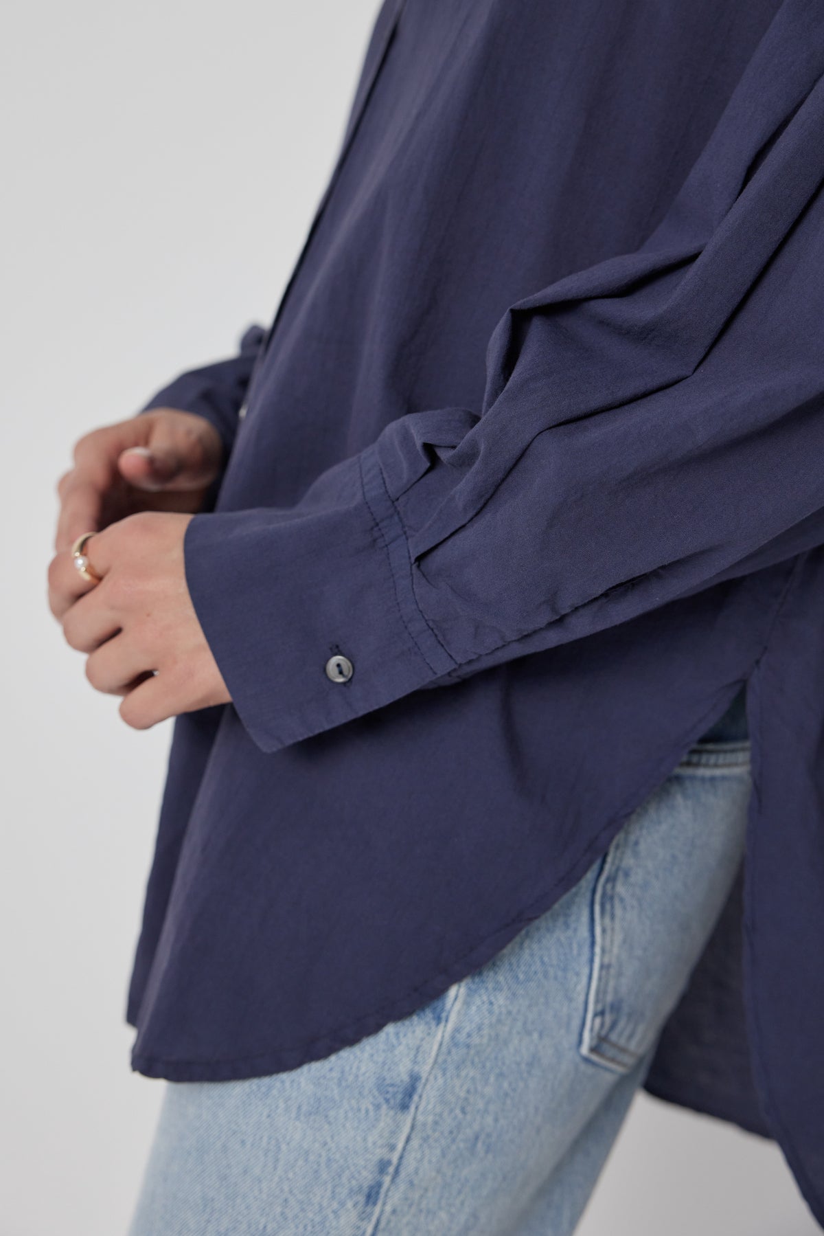   A person wearing an oversized navy blue Velvet by Jenny Graham REDONDO BUTTON-UP SHIRT and blue jeans, with a focus on the shirt's cuff and button details. 