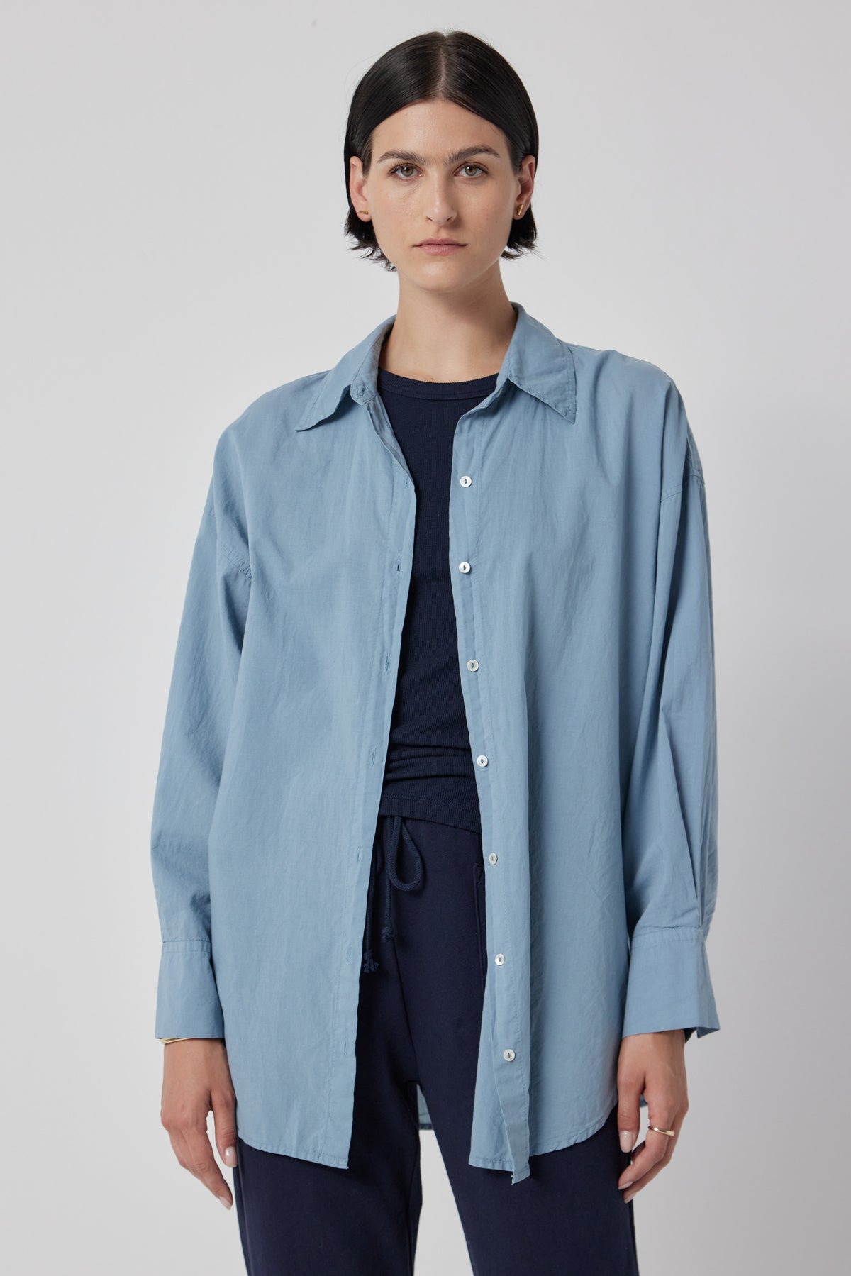   A woman wearing an oversized blue cotton Velvet by Jenny Graham Redondo Button-Up Shirt and pants. 