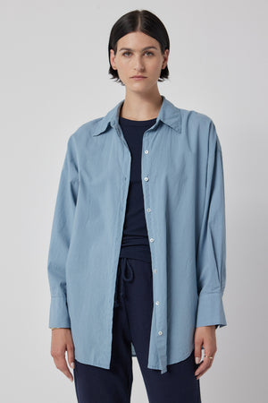 A woman wearing an oversized blue cotton Velvet by Jenny Graham Redondo Button-Up Shirt and pants.