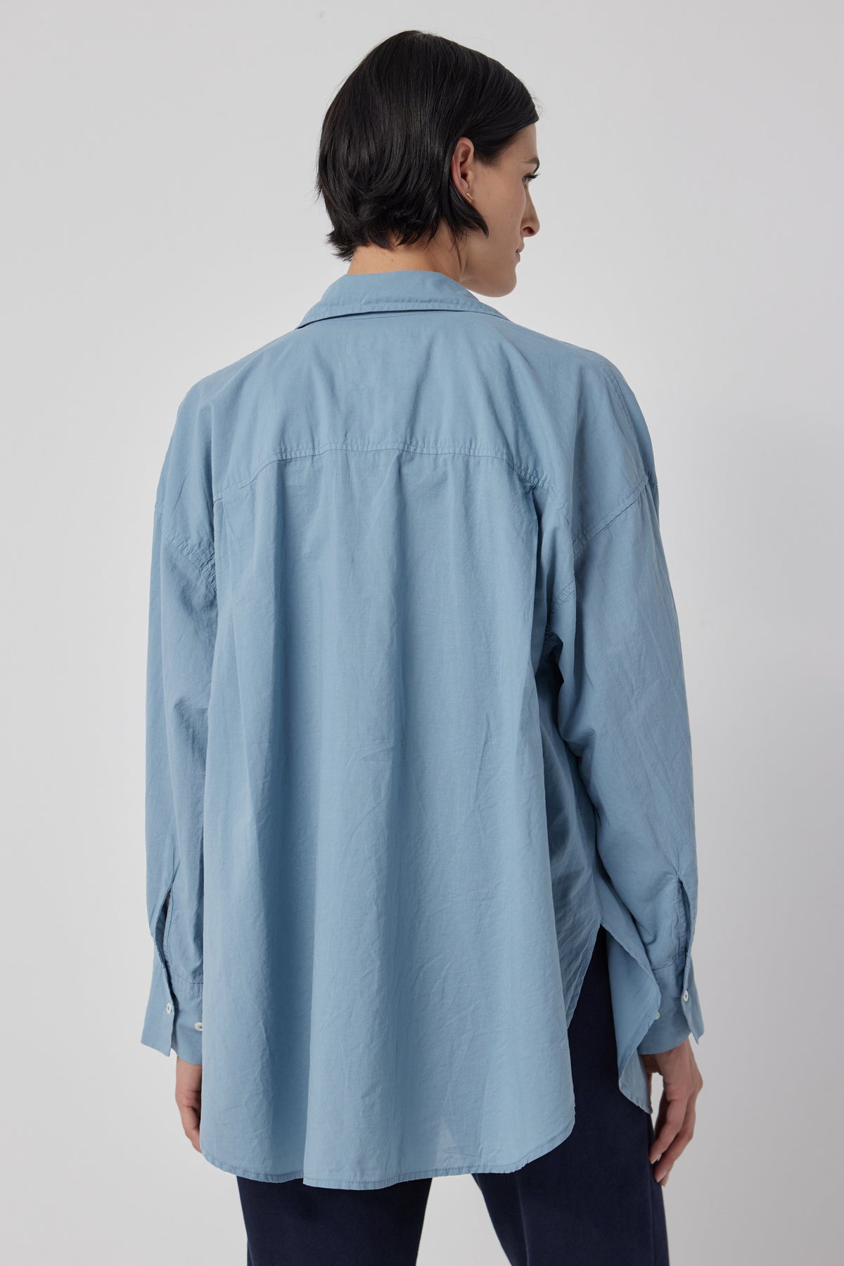   The back view of a woman wearing an oversized blue cotton Velvet by Jenny Graham REDONDO BUTTON-UP SHIRT. 