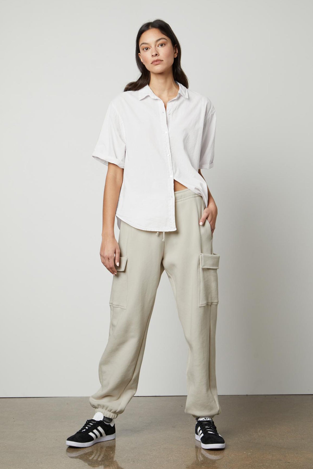   The model is wearing a white shirt and LUMI DRAWSTRING WAIST SWEATPANT cargo pants from Velvet by Graham & Spencer, perfect for everyday wear or running errands. 